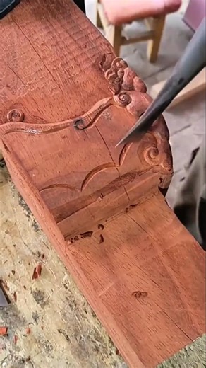carving a beautiful pattern manually into a dark wooden surface using a sharp metal hand chisel tool