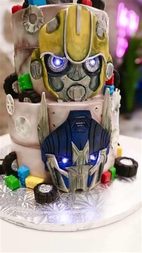 A Transformers themed birthday cake featuring Bumblebee and Optimus Prime with glowing details and