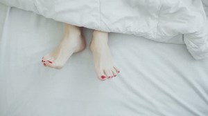 clip-1023754879-female-legs-bed-view-above-white-bedding