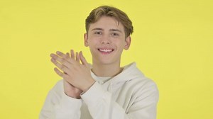 Young Man Clapping, Applauding on Yellow Background