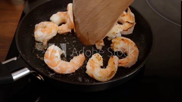 Shrimp frying in a pan, seafood grill, kitchen preparation, tasty meal.