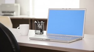 Laptop computer with blue screen in office