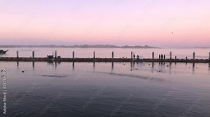 People catching crabs on docks in Bandon Oregon during a beautiful sunset over the Coquille River. Boat doing by. Peaceful maritime scene