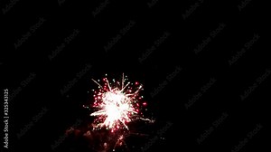 Static view of falling leaf style fireworks trickling down through the night sky, shimmering as other fireworks shoot up and explode