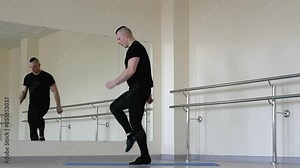 A professional dancer stretches during training performing body stretching exercises. A ballet dancer warms up in the fitness room, a man in jazz shoes and a classical uniform.