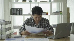Asian young man excited about successful business Young businessman using computer in office He was energetic and excited about what he was watching on his laptop.