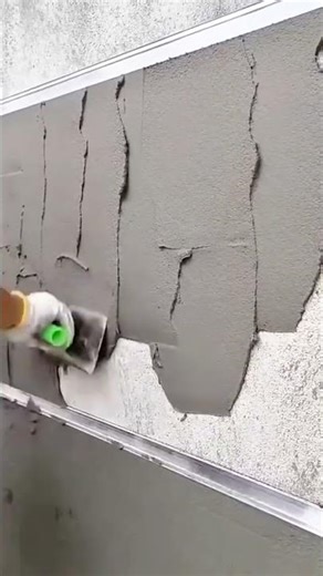 Carefully smoothing fresh cement on a wall surface to achieve a clean and even construction finish