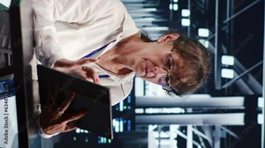 Vertical video Skillful IT consultant working in high tech headquarters housing GPU dedicated servers that can process AI tasks with high efficiency, monitoring rigs used for machine learning showing