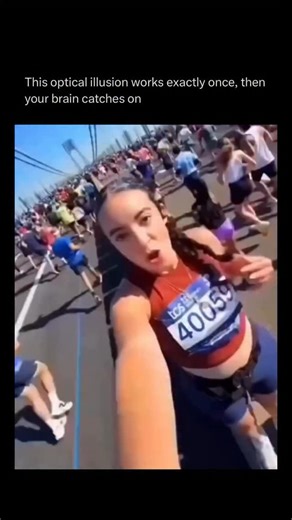 How Everything Works on Instagram: "At first glance, it looks as if this woman is gliding down the street on an invisible conveyor belt—but she’s not moving at all. The marathon runners flooding past her on both sides trick your brain into reversing the roles: instead of recognising their motion, your mind decides she’s the one sliding forward. It’s a classic example of induced motion, or vection—when your eyes take in a scene full of movement and your brain chooses the wrong “main character.” O