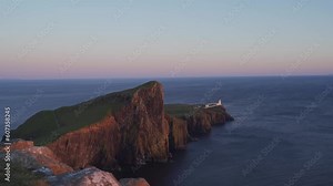 Neist Point Lighthouse on a cliff over a background of a beautiful sunset