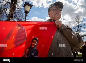 Moscow, Russia. 1st May, 2022. A man holds a banner with a portrait of the Ukraininan babushka with a Soviet Flag during a rally of the Russian Communist Party supporters marking International Workers' Day in Teatralnaya Square in central Moscow, Russia. The Red Banner Grandma, an elderly woman who was captured on video greeting Ukrainian servicemen with a Soviet Red Banner and mistaking them for Russian Stock Photo - Alamy