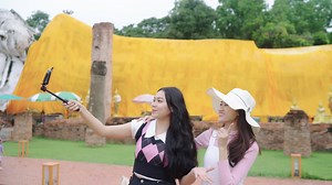 Download Two Asian women backpack are bloggers vlog creating temple travel content in Ayutthaya. Have fun, smile during holidays. for free