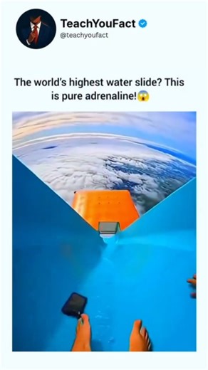 teachyoufact on Instagram: "The video shows a first-person perspective of someone sitting at the top of a bright blue water slide that appears to be located high above the earth, well above a thick layer of white clouds. A person in an orange safety vest stands at the start of the slide as the individual prepares to go down. As they push off and begin sliding, they quickly gain incredible speed, and their phone can be seen sliding down ahead of them. The slide suddenly ends, launching the person