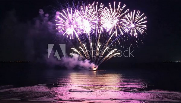 4K drone aerial fireworks show above a calm lake at night. Bright colorful fireworks exploding in the sky