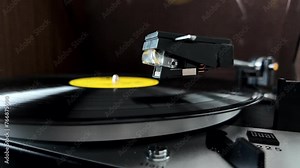 The vinyl record stops playing and the record player needle is removed to stop playback. Close Up view. Slow motion video.