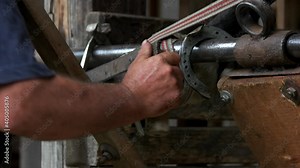 Blacksmith shoeing a horse. Farrier trimming horse hoof with a metal tool. Preparing horse hoof for shoeing.