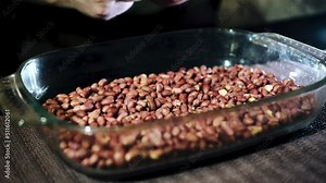 The guy eats nuts from a large cup standing on the table. Close-up shooting