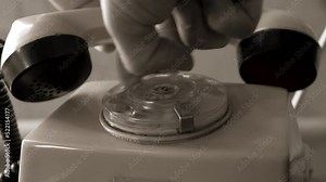 Old phone. Rotary dial telephone on table or desk in room or office cabinet. Plastic housing and handset. Human hand use rotary dial initiating telephone call