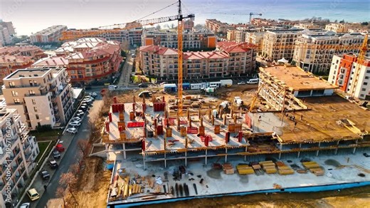 Aerial perspective of residential development with tower cranes. View of a building under construction overlooking the sea