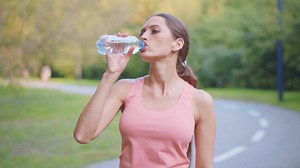 a woman is drinking water from a bottle