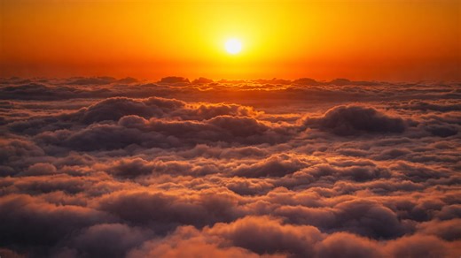 The sun rising gently over a quiet cloud landscape