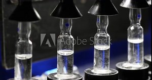 Close up of ampoule production machine. vaccine manufacturing process. injections in glass vial in a pharmaceutical factory making process under blue light with latest hi tech machinery