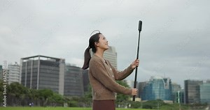 Woman use 360 degree camera to take video at park