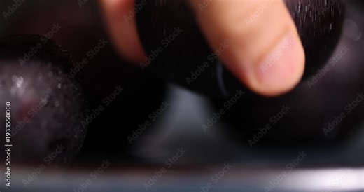 black fresh juicy plums on the kitchen table, several beautiful clean black plums on the table, the plums are covered with a lot of drops of water
