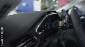 Zoom out from control panel to interiors of luxurious brand new vehicle in car dealership. Stylish expensive automobile in auto showroom indoors. Design and luxury concept