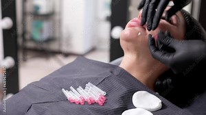 An adult woman undergoes a thread lifting procedure in a cosmetology clinic. Anti-aging facial rejuvenation. A cosmetologist implants cosmetic threads under the skin to eliminate facial ptosis.