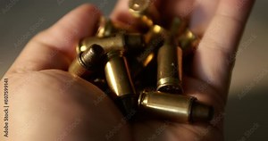Close-up of a fistful of empty bullet shell casings being held in one hand.