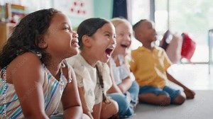 Line of laughing primary or elementary school students sitting on floor during classroom lesson - shot in slow motion
