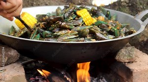 the process of cooking green mussels or Perna viridis, mixed with corn and spicy stir-fry spices.