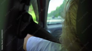 Rear view of a female passenger in a passenger car while traveling on a country highway. Enjoy a summer car ride.