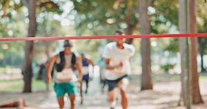Fitness, celebration or sports runner at the finish line with arms raised for victory, achievement or exercise goals. Winning event, fast or happy man excited by running, marathon training or workout