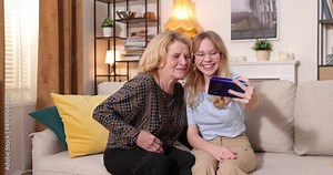 Happy grandmother with her granddaughter. He relaxes at home together. Resting on the couch. Two generations of grandparents and grandchildren spend time together