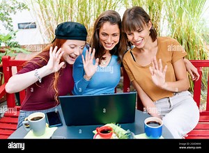 Three happy smiling young women having a video call on a laptop computer waving in greeting at the screen for long distance communication Stock Photo - Alamy