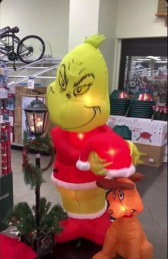 Gemmy animated Christmas inflatable Grinch putting hat on Max