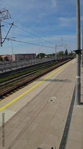 This is a time-lapse video taken from the perspective of a train station. The video shows the station platform, the tracks, and the surrounding area. The video is sped up, so the movement of people