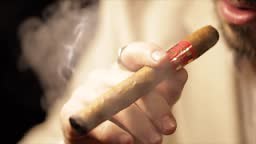 Close Up Man Smoking Cigar Slow Motion. a close up view of the end of...