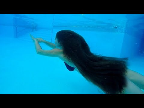UNDERWATER Swimming Rapunzel. Beautiful girl with very long hair swims in the pool