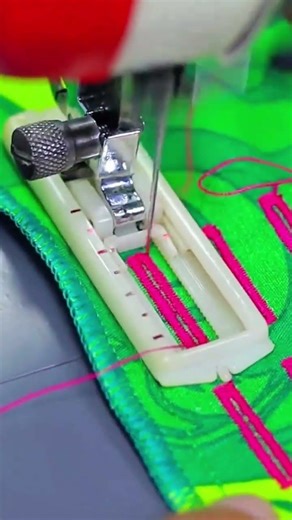 making a buttonhole on green fabric with pink thread using an automatic sewing machine foot tool