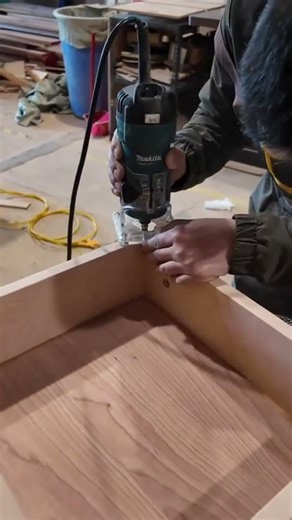 Cutting and trimming several light brown wood boards precisely using an electric power hand router