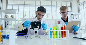 Close up scene video of handsome Caucasian male scientists doing an experiment in a laboratory room to finding new discoveries together. One of them recording a result.