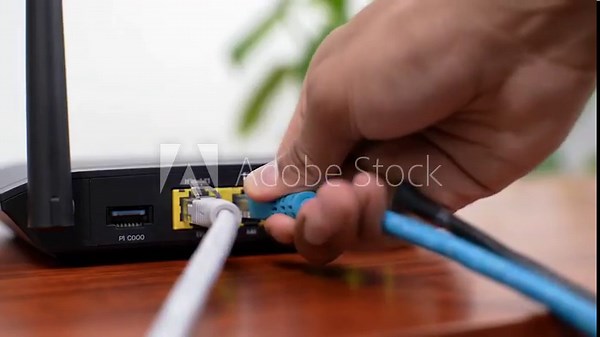 Establishing a Wired Network Internet Connection. Hand Plugging Blue Cable into Router Port. Completing a Home or Office Network Setup.