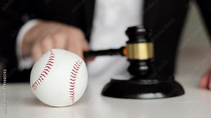 Judge's hand banging a gavel. Baseball ball on the table. Corruption in baseball.