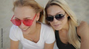 Girls best friends makes finger heart, having fun on a beach resting together at summer holidays in slow motion