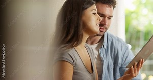 4K Cheerful couple using computer tablet at home & smiling at what they see on screen. Slow motion.