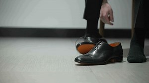 Young Man Donning Stylish Boots. Fashion and Style Moment. Young Man Experiences a Fashionable Transition. Putting on a Pair of Stylish Booties with Confidence and Flair.