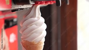 Soft serve being dispensed into a cone at a shop